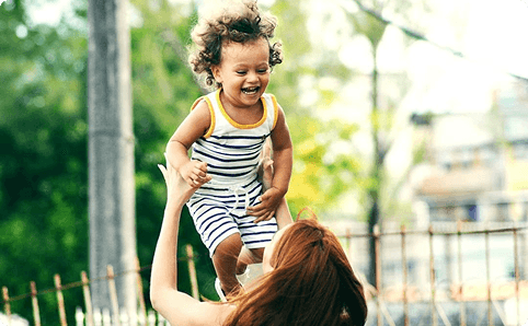 Parent lifting a smiling child outdoors near Friendswood